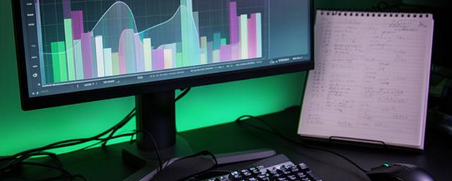 Gaming keyboard and monitor showing a PC frame-rate benchmark beside a notebook